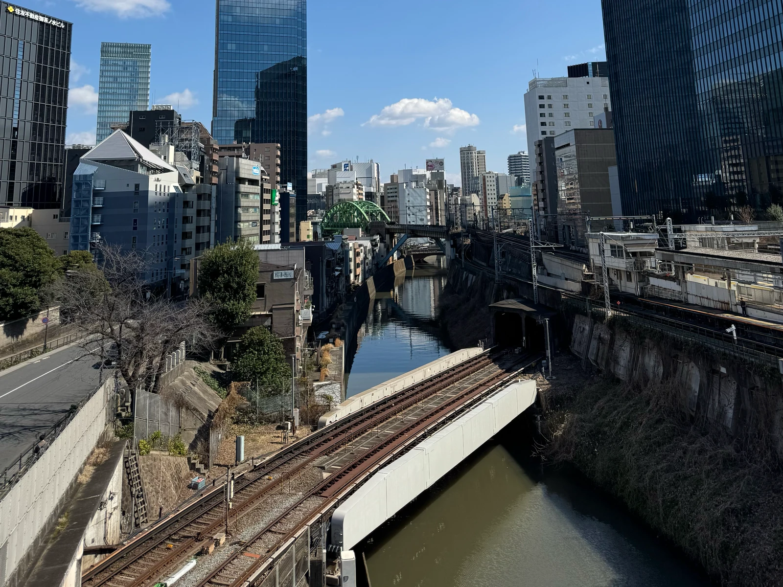 Railway bridges crossing a river between city buildings.
